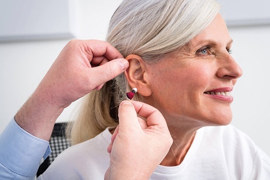 Ältere Frau bekommt ein modernes Hörgerät angepasst, Hörakustiker berät zur Hörhilfe.